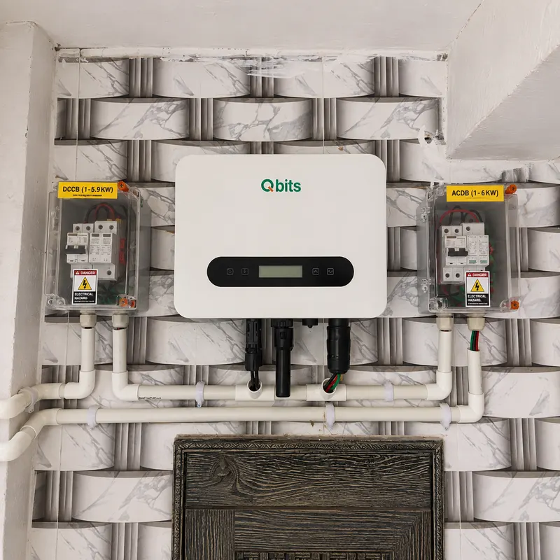 Qbits solar inverter installed on a marble-clad wall above a carved wooden door, with DCCB and ACDB boxes and PVC conduit